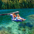 Adult relaxing on a blue-and-white Intex Floating Recliner on a clear lake