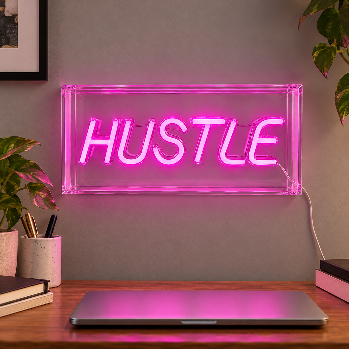 Elements HUSTLE pink LED sign displayed on a home-office wall