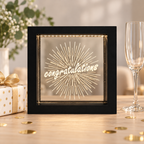 Black Congratulations LED light box on a celebration table with a gift and confetti