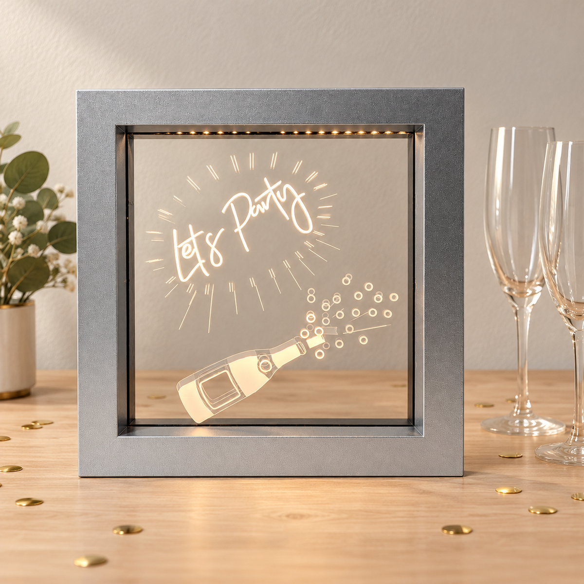 Silver Let's Party LED light box on a party table with champagne flutes and confetti