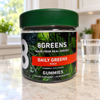 8Greens Daily Greens Peach, 50-gummy jar on a kitchen counter beside a glass of water