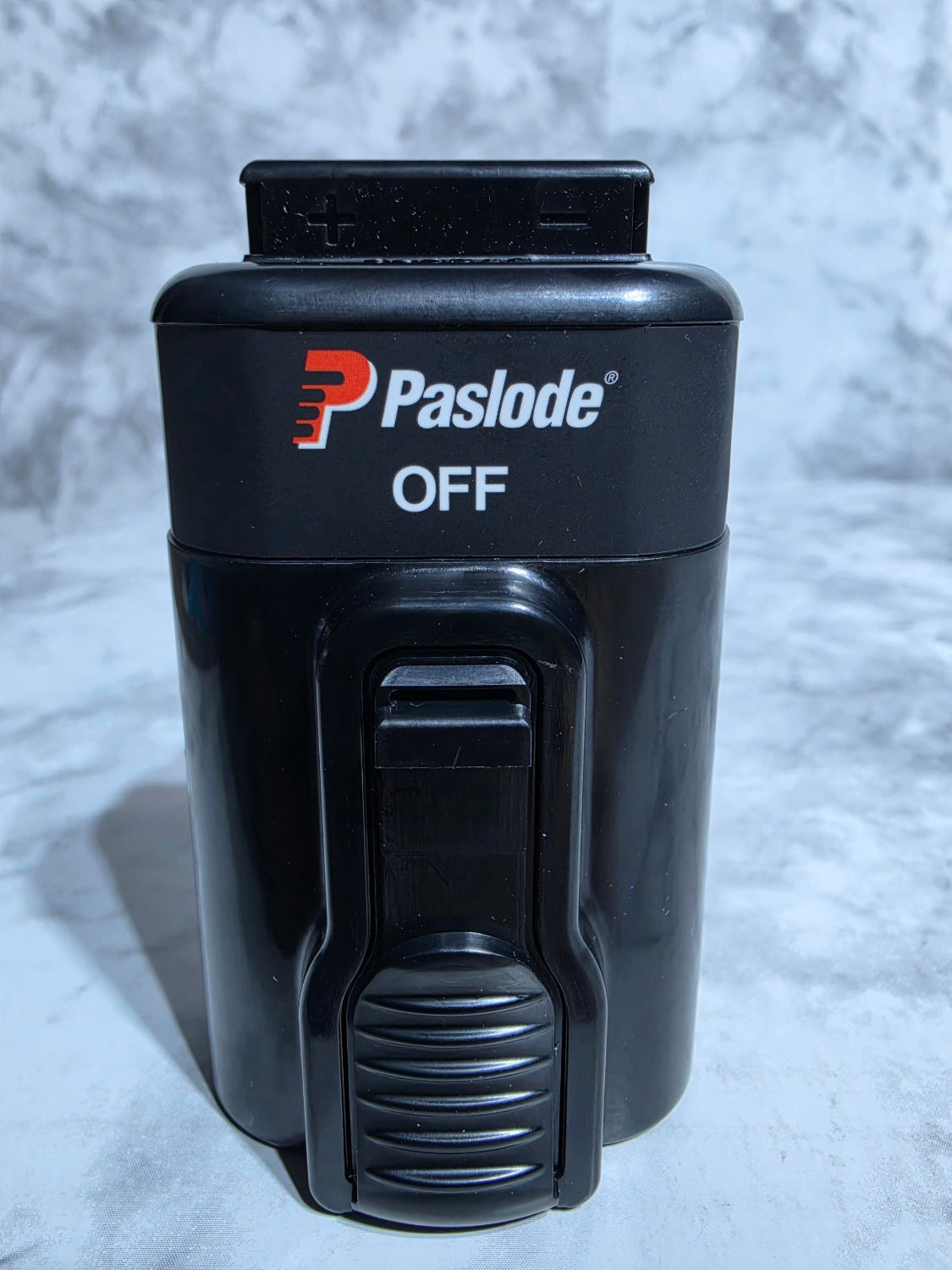 Black Paslode nail gun on a textured gray background