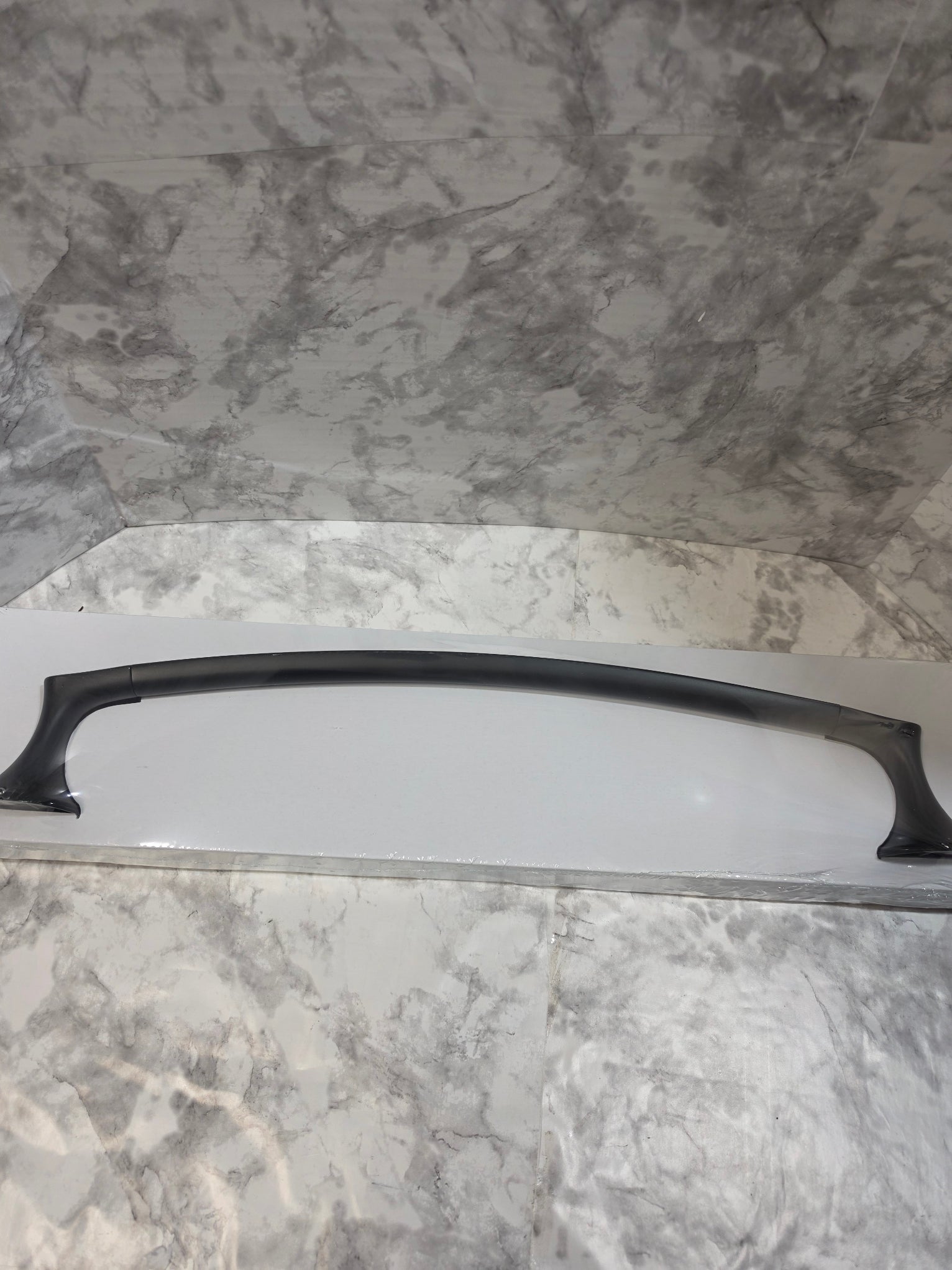 Black handle on a white surface against a marble-patterned wall