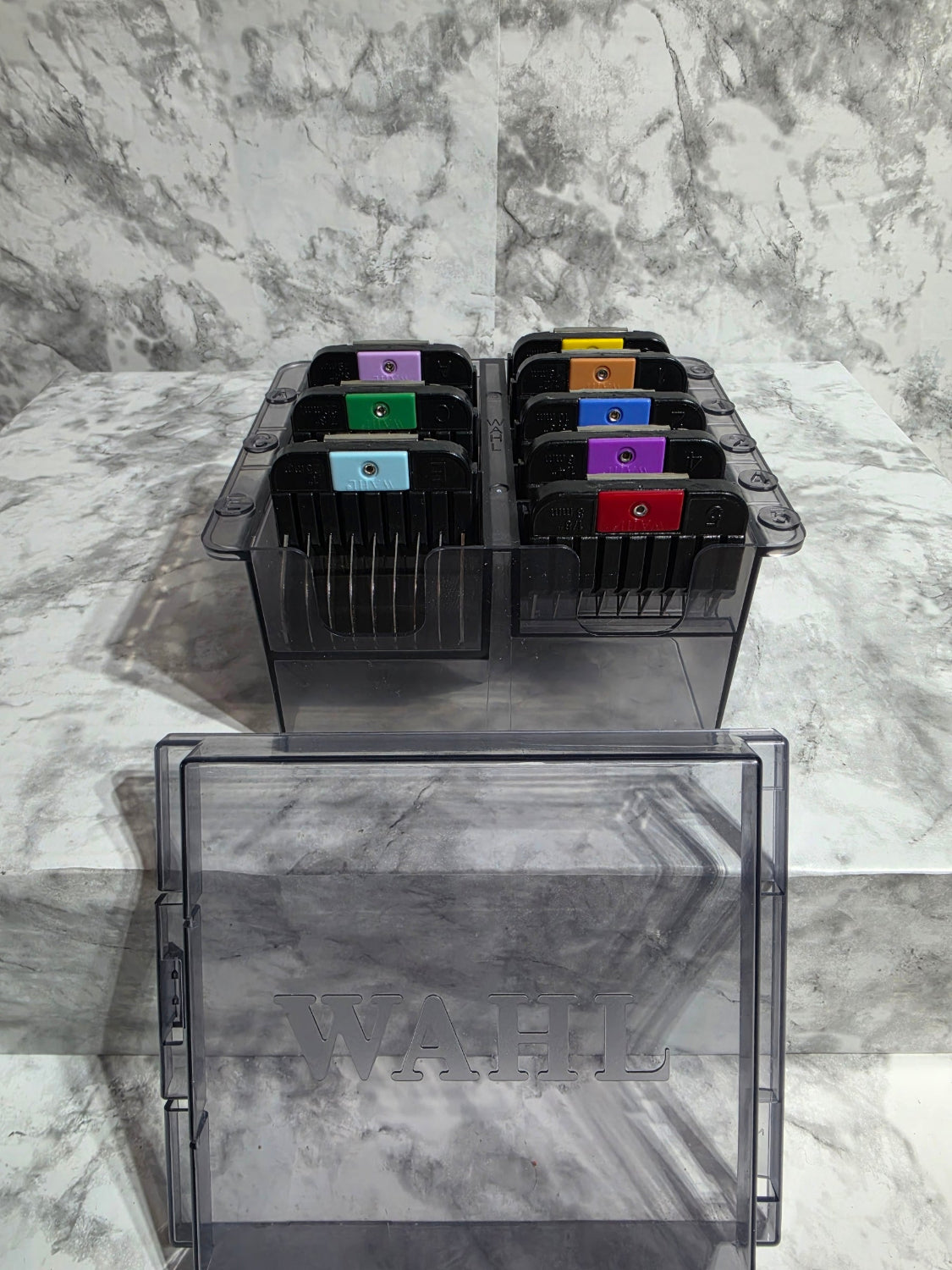 Black printer cartridge holder with colorful cartridges on a marble surface