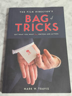 Book cover of 'The Film Director's Bag of Tricks' by Mark W. Travis on a marble surface.