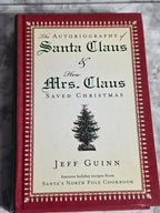Book titled 'The Autobiography of Santa Claus & Mrs. Claus How Christmas Saved Christmas' by Jeff Guinn on a marble surface.