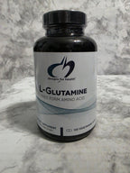 Bottle of L-Glutamine supplement on a marble surface