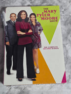 DVD box set cover of 'The Mary Tyler Moore Show' with a family photo on a gray surface