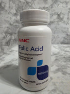 GNC Folic Acid supplement bottle on a marble surface