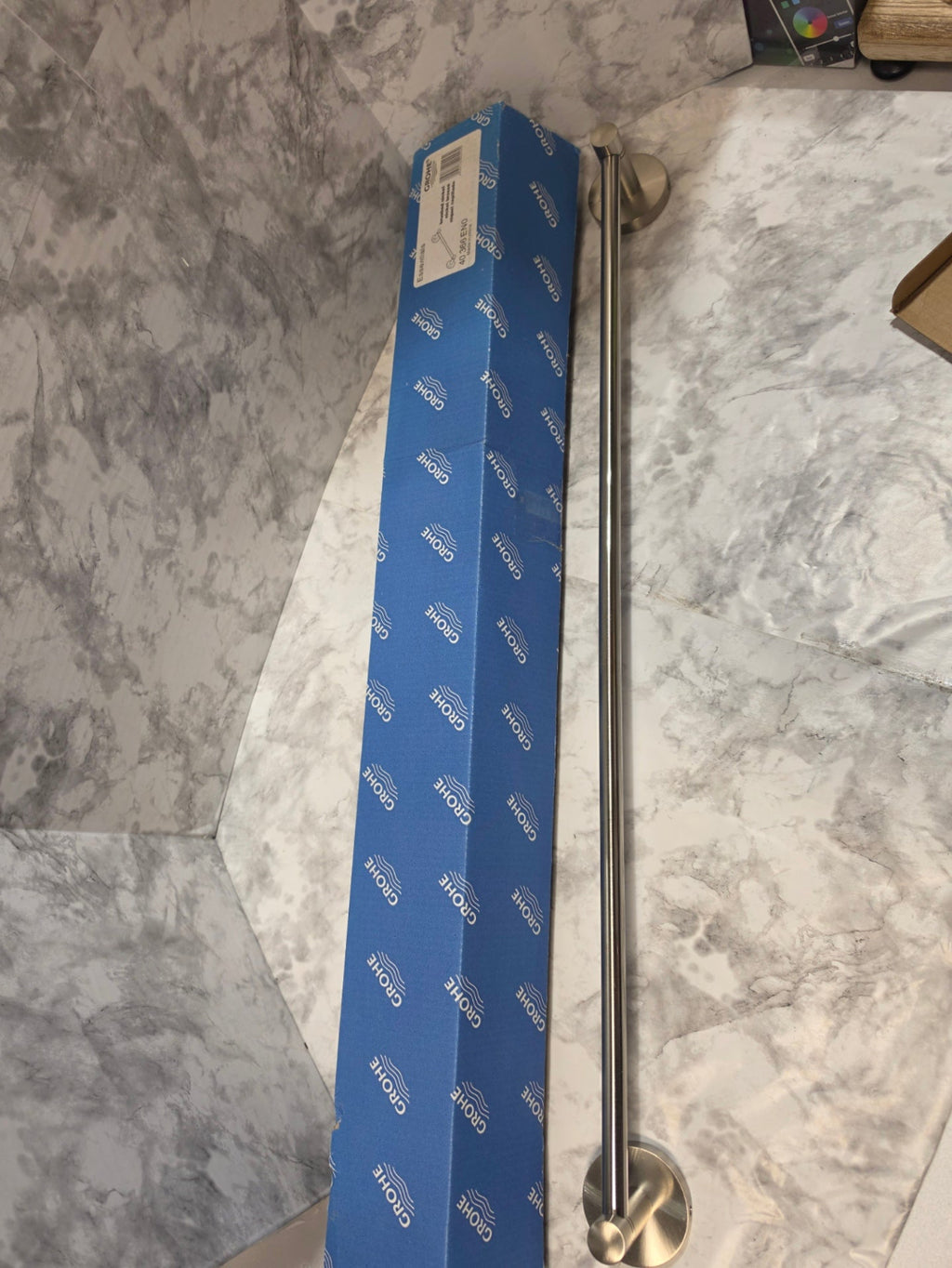 Metal towel bar on a marble countertop with a blue box in the background.