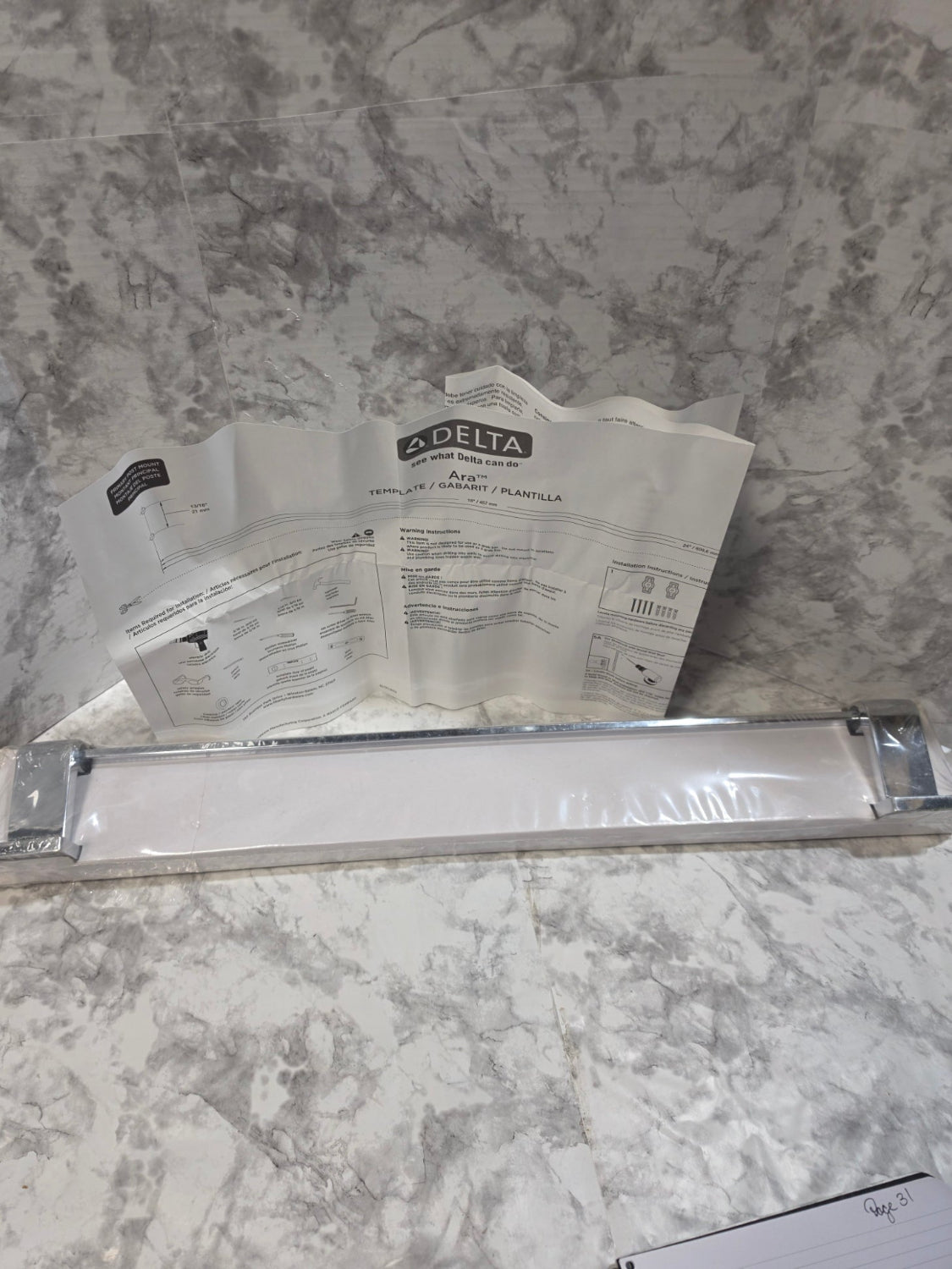 Metallic handle on a marble surface with a Delta brand leaflet.
