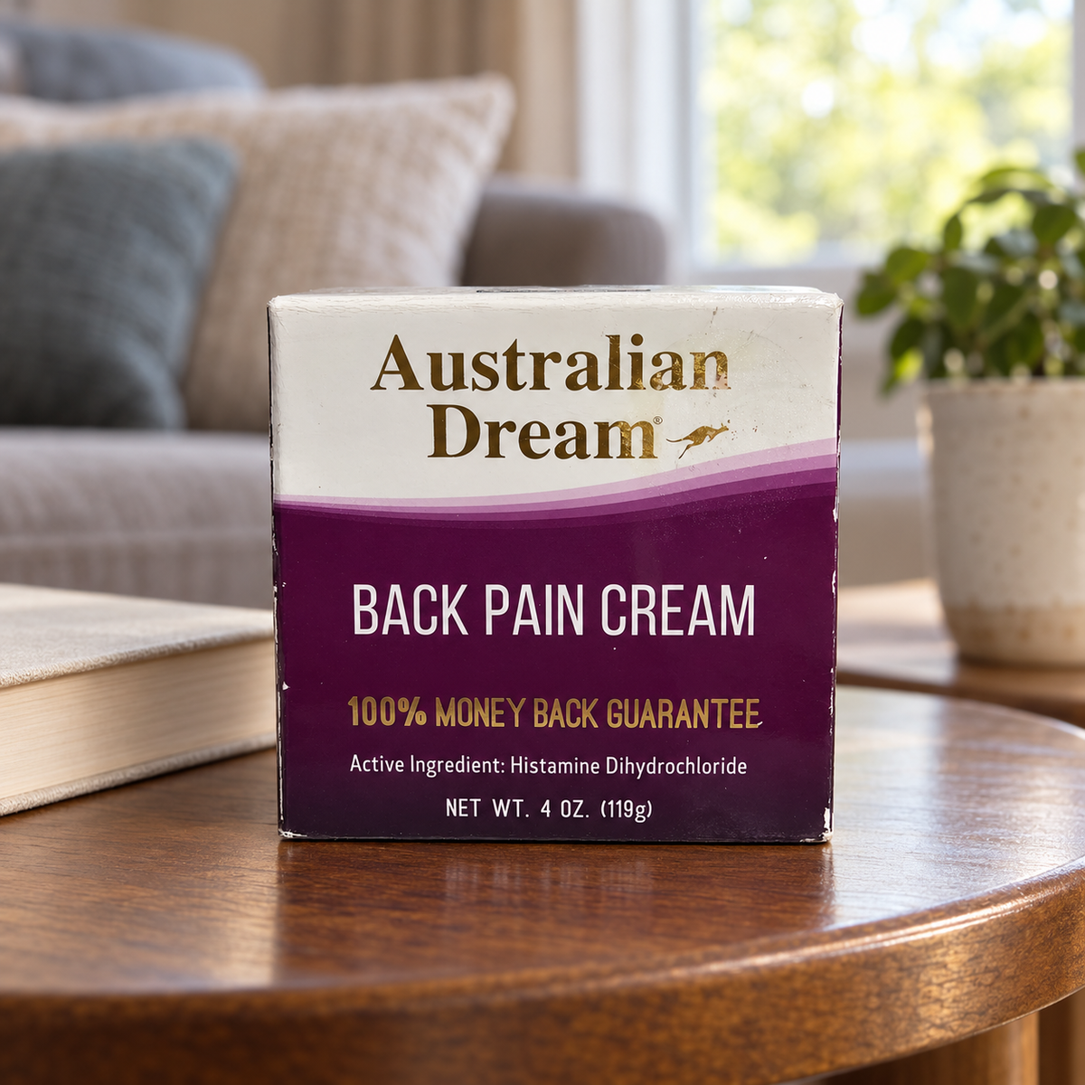 AI-generated lifestyle illustration: closed Australian Dream Back Pain Cream 4 oz carton on a living-room side table; furnishings and book are props, not included.