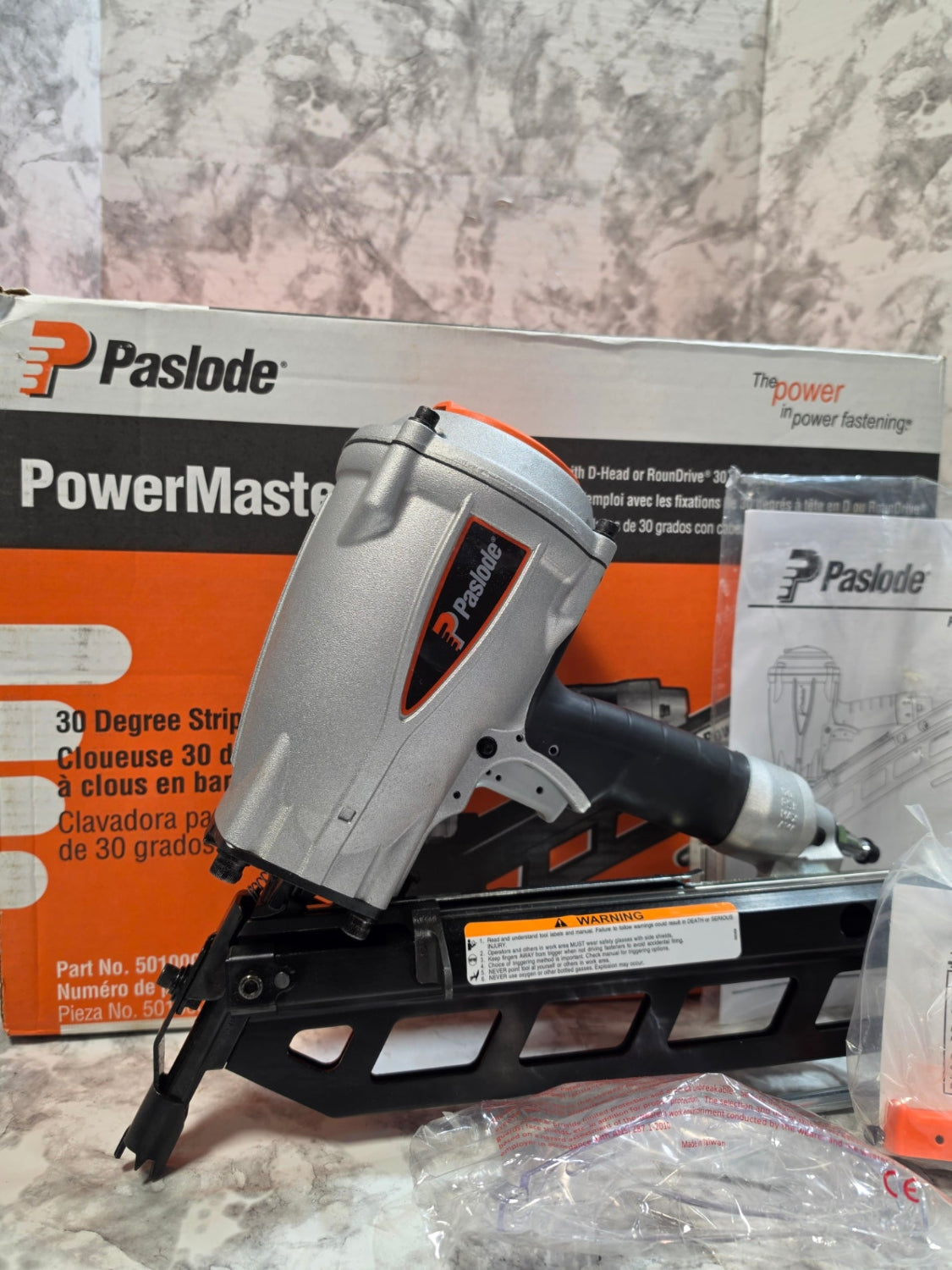 Paslode nail gun on its packaging with a marble-like background