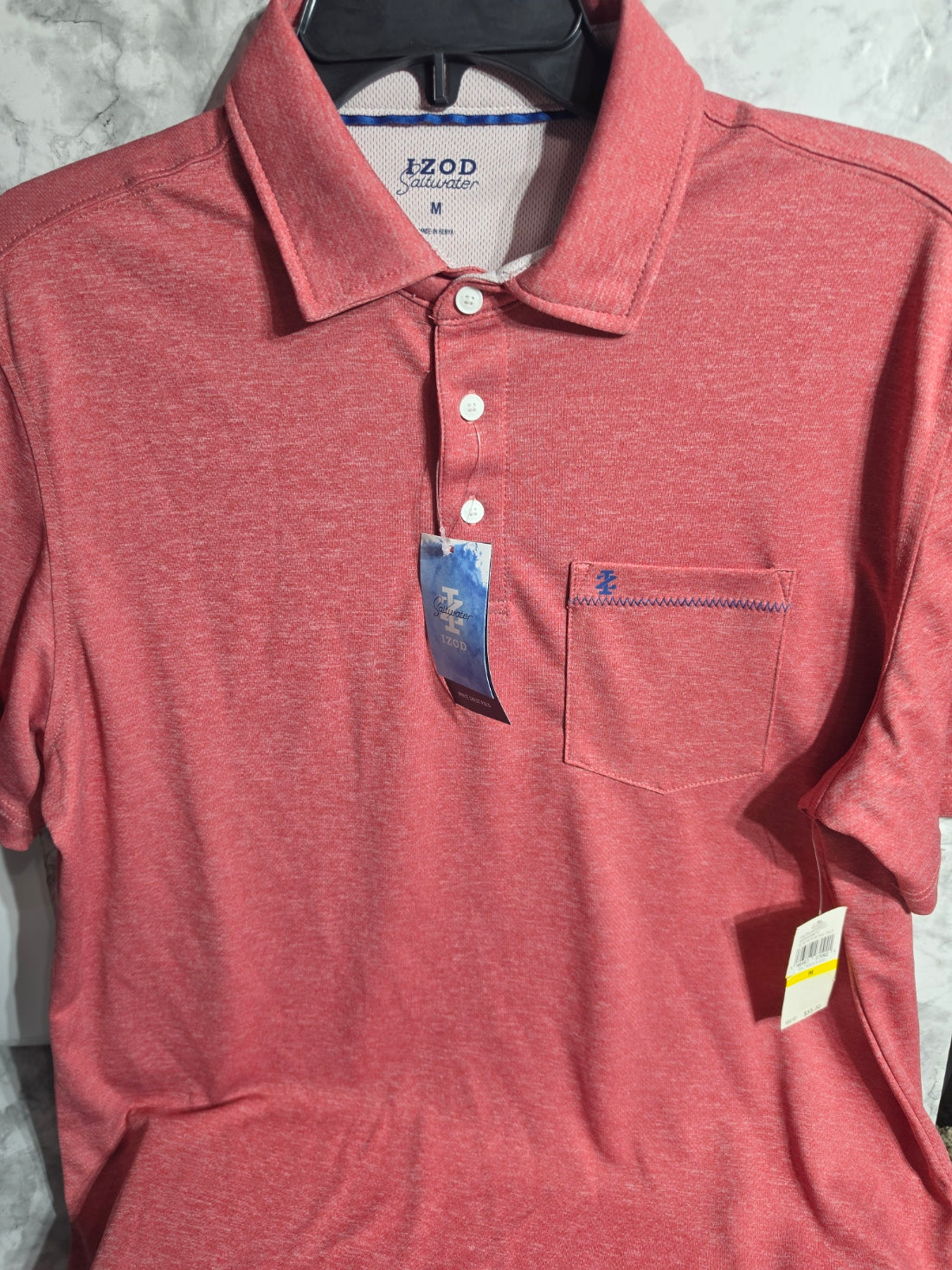 Pink polo shirt with brand labels on a marble surface