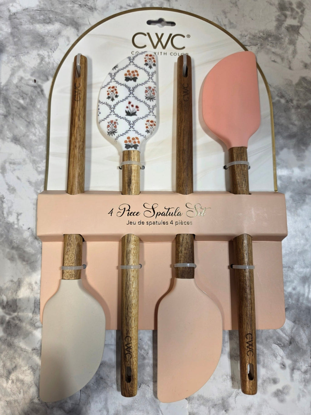Set of wooden spatulas with pink and beige handles on a marble surface