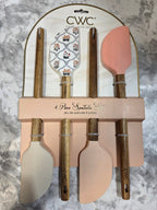 Set of wooden spatulas with pink and beige handles on a marble surface
