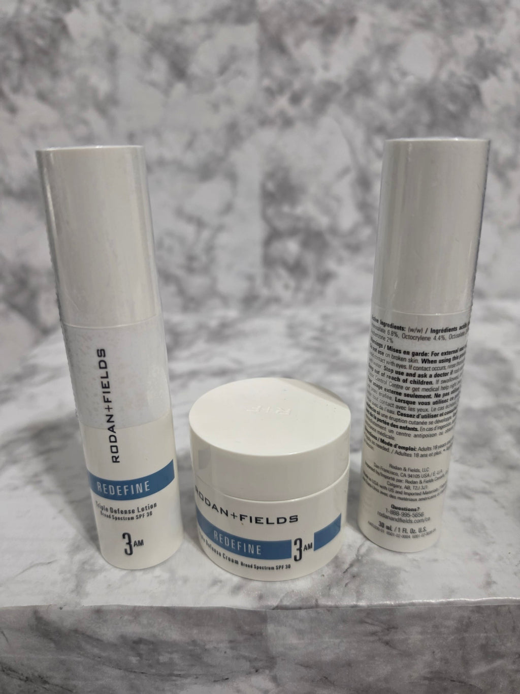 Three skincare products on a marble surface