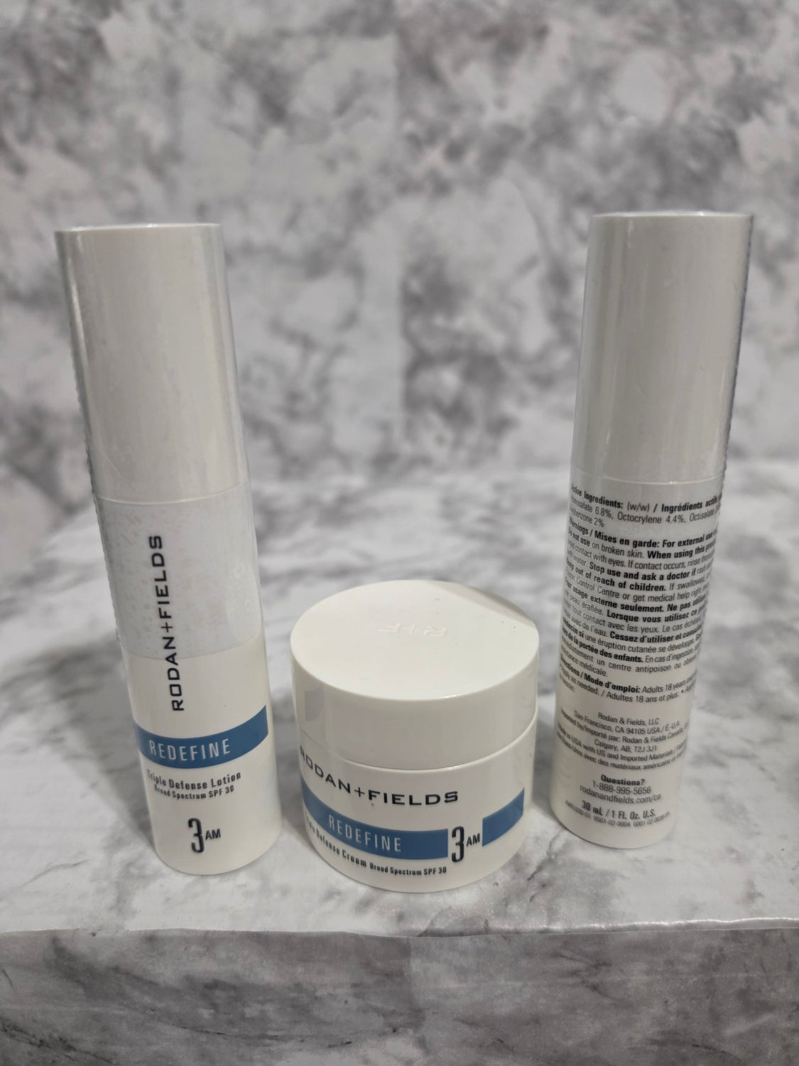 Three skincare products on a marble surface