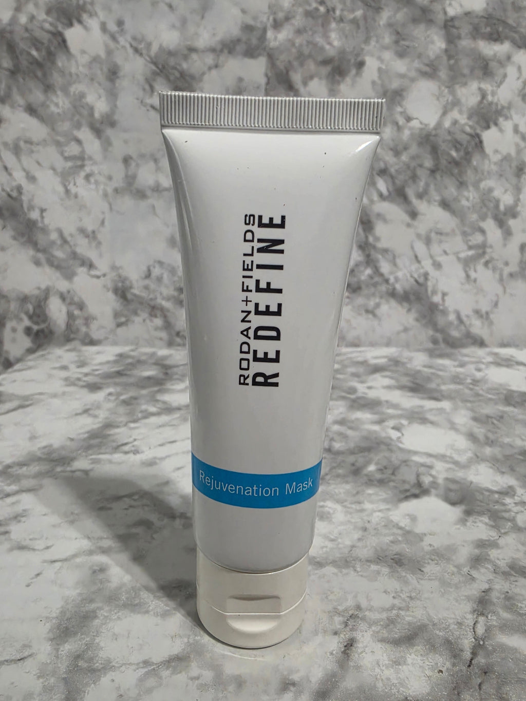 Tube of 'REDEFINE' face mask on a marble surface