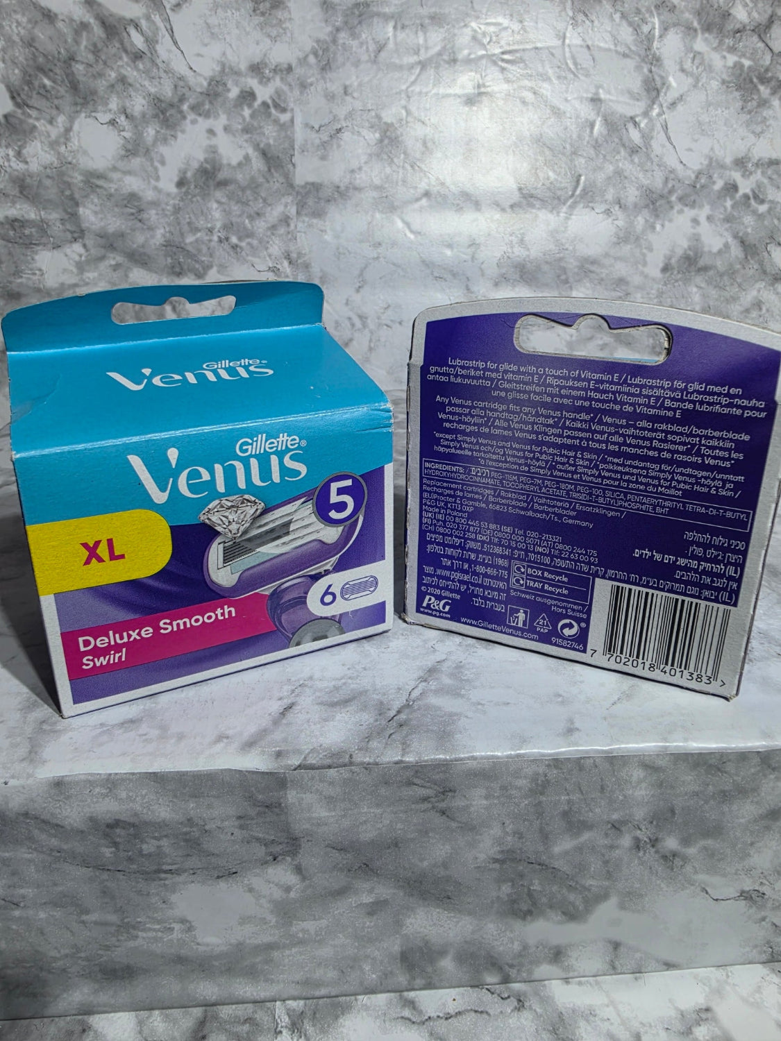 Two packages of Gillette Venus razors on a gray marble surface