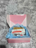 Actual curated at-home facial and spa gift kit in an open pink presentation box with blue tissue and included items
