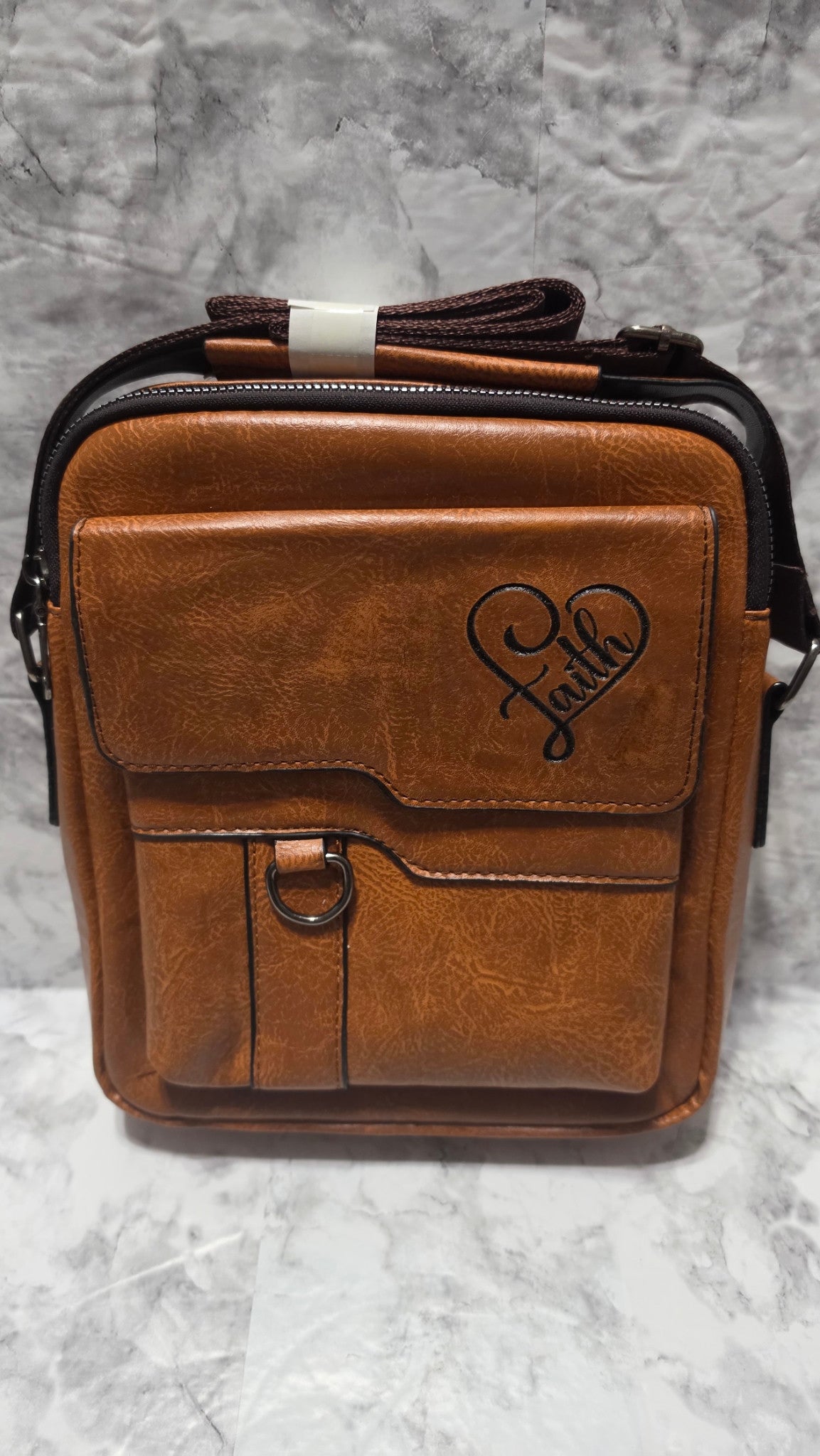 Actual Khaki bag with the word Faith laser-engraved inside a heart on its front flap