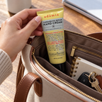 AI illustration of Adamia 3 oz yellow hand cream tube being packed into a tote bag; props not included