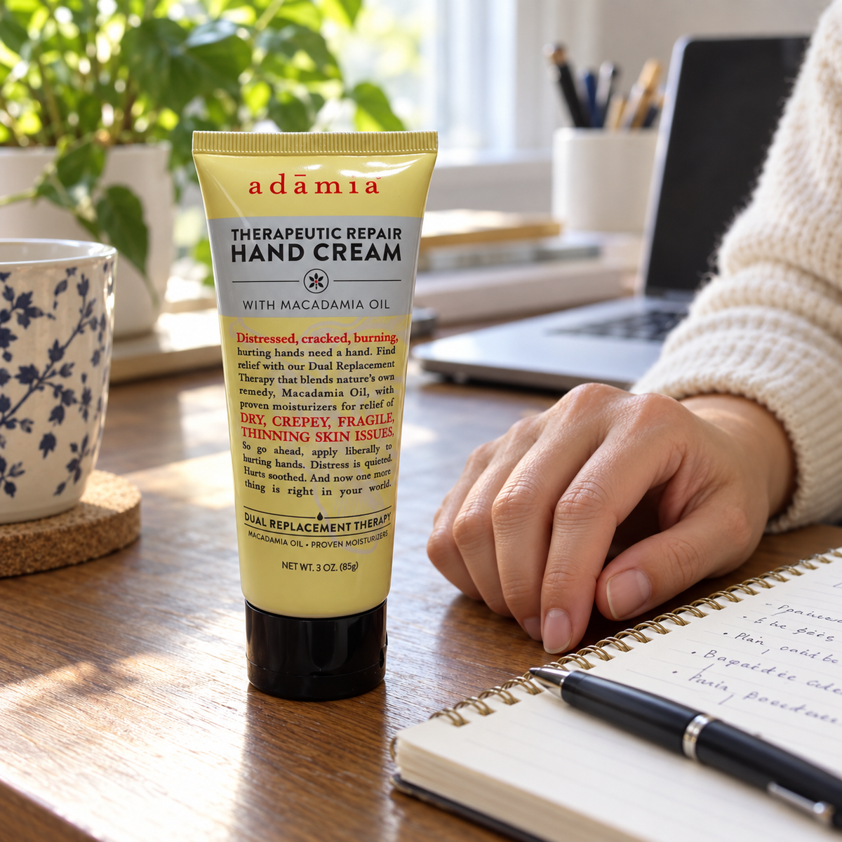 AI illustration of Adamia 3 oz yellow hand cream tube on a desk beside a notebook; props not included