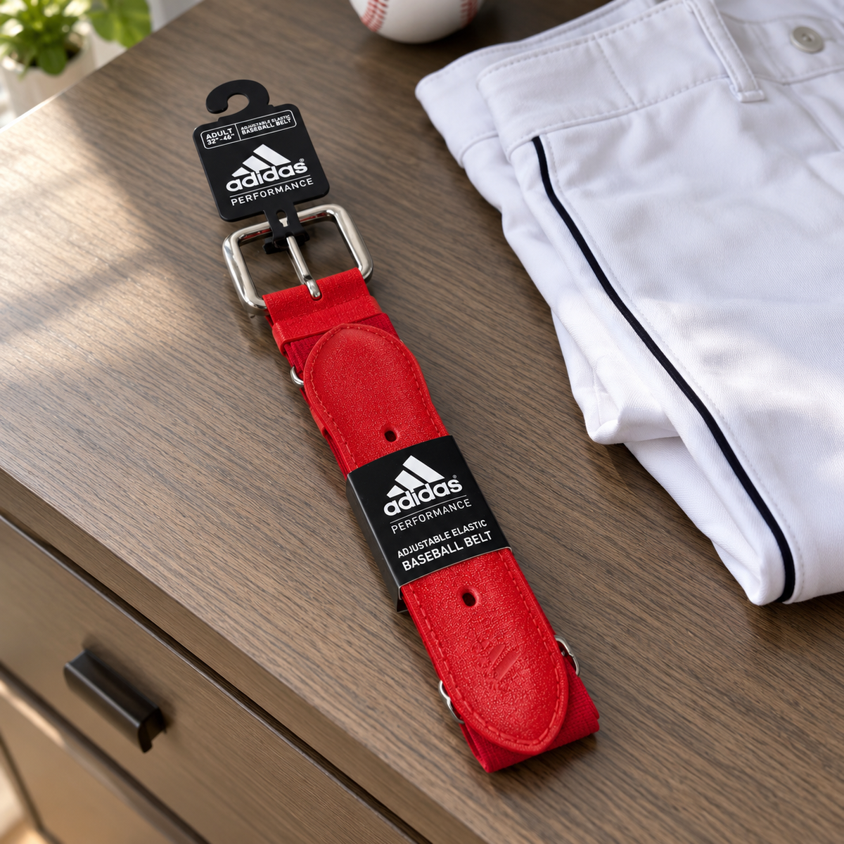 AI-styled red Adidas Performance adult baseball belt with tags on a uniform dresser