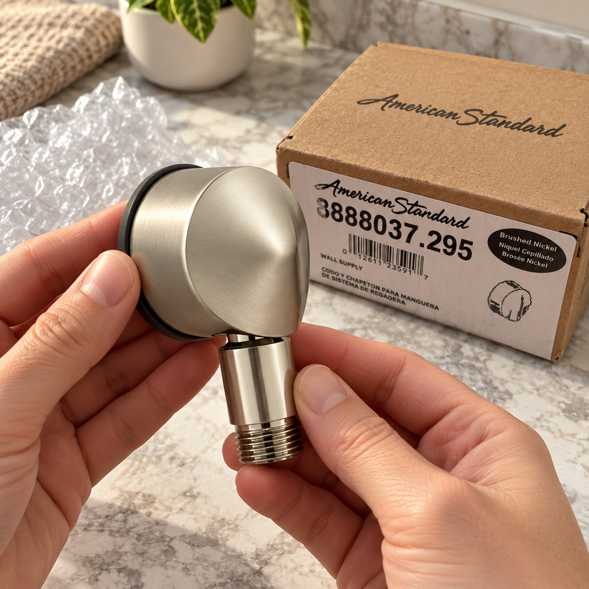 American Standard 8888.037.295 brushed nickel wall supply elbow, handheld inspection, AI-assisted illustration