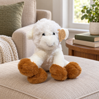 AI-generated lifestyle scene: white Animal Adventure lamb plush with brown hooves on an ottoman; furniture and books not included.