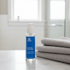 Arbonne Bio-Hydria Liquid Serum 1 fl oz on a marble vanity beside folded towels