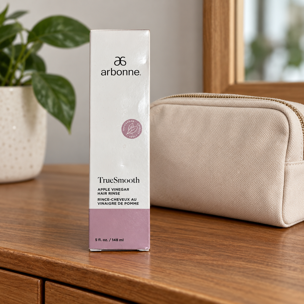AI lifestyle illustration of the closed Arbonne TrueSmooth Apple Vinegar Hair Rinse 5 fl oz carton beside a travel pouch; pouch not included.