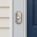 AI illustration: Baldwin polished nickel Arch doorbell button on fixed light entry trim beside a navy door