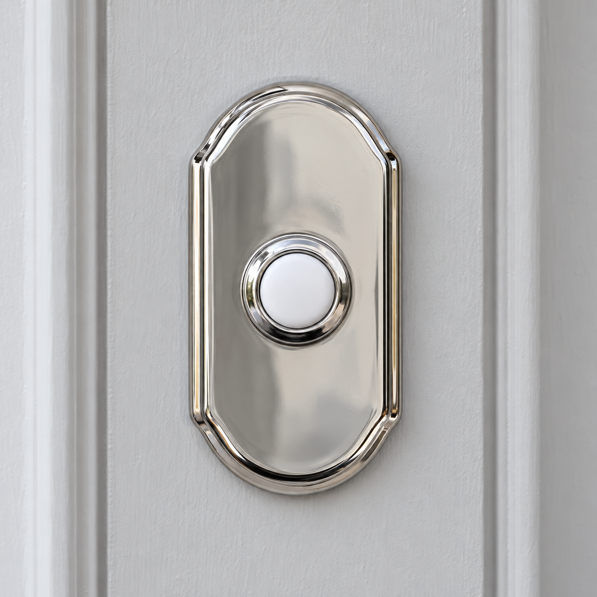 AI illustration: close-up of a Baldwin polished nickel Arch doorbell button with a white round pushbutton on light trim