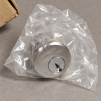AI illustration: Close view of the Baldwin satin nickel cylinder face inside clear plastic packaging