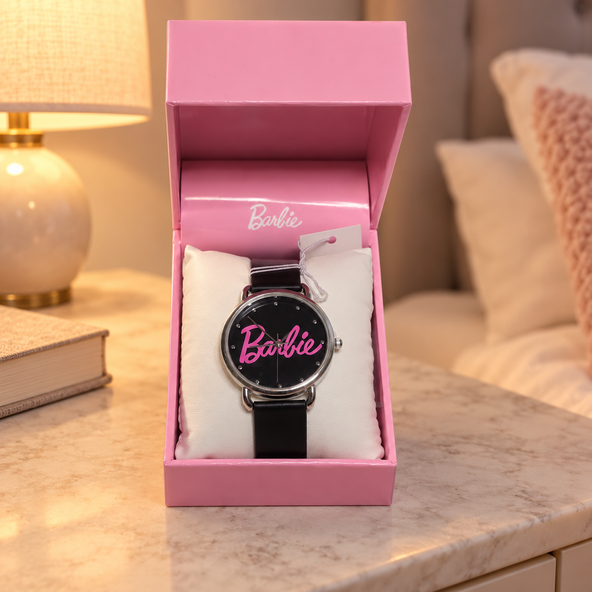 AI illustration of one black-dial pink-script Barbie watch with silver-tone case and black strap in its original presentation box on a bedside table; props not included