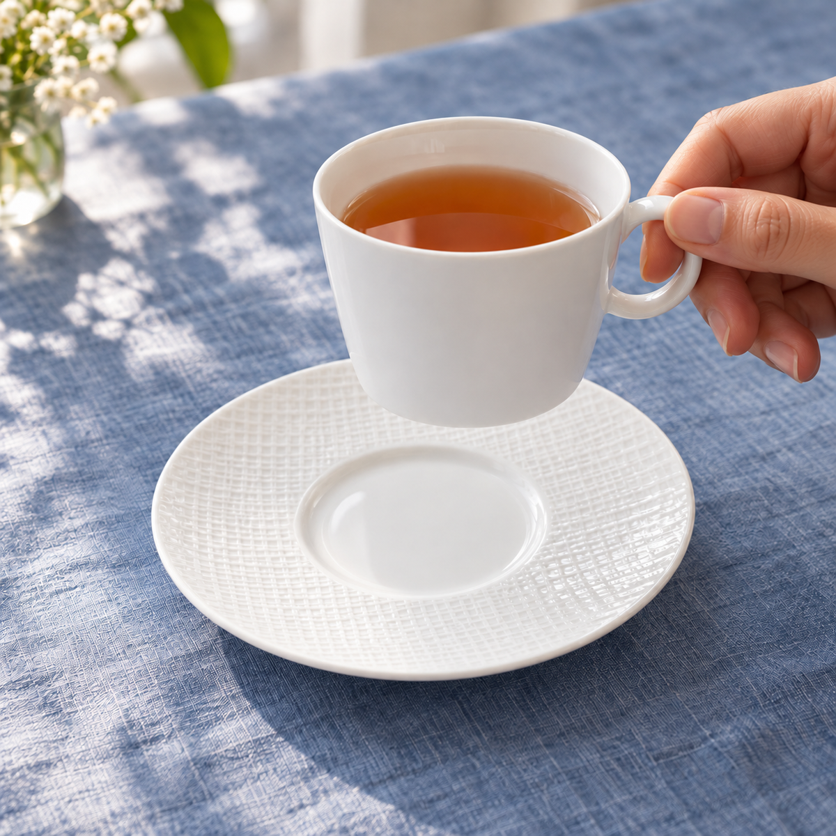 Bernardaud Organza 5.7-inch tea saucer as a hand lifts a matching teacup; saucer only, cup not included.