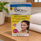 AI-generated wooden shelf scene of the worn Bioré Witch Hazel 18-strip retail box beside a towel.