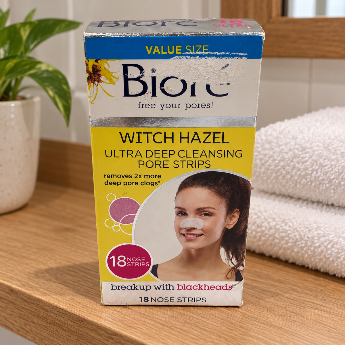 AI-generated wooden shelf scene of the worn Bioré Witch Hazel 18-strip retail box beside a towel.
