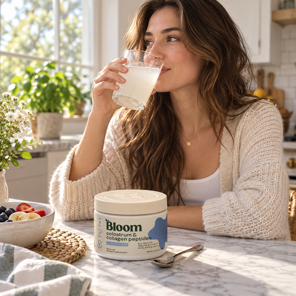 Woman drinking a mixed beverage with Bloom Colostrum and Collagen Peptides nearby