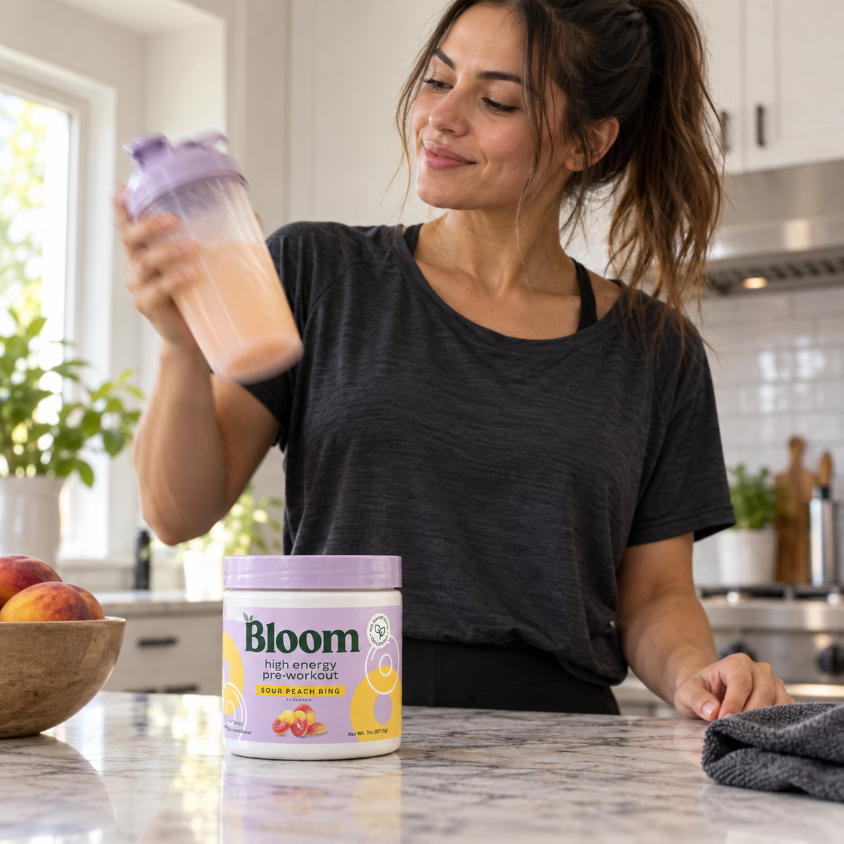 Shaking a pre-workout drink with a Bloom Sour Peach Ring tub on the kitchen counter