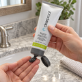 Dispensing Mary Kay Clear Proof charcoal mask onto fingertips from the open flip-top tube