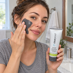 Applying a charcoal-gray mask to the cheek while holding the Mary Kay Clear Proof tube