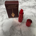 Charlotte Tilbury Hollywood Vixen mini lipstick with open red tube, cap and original box on a marble-pattern background