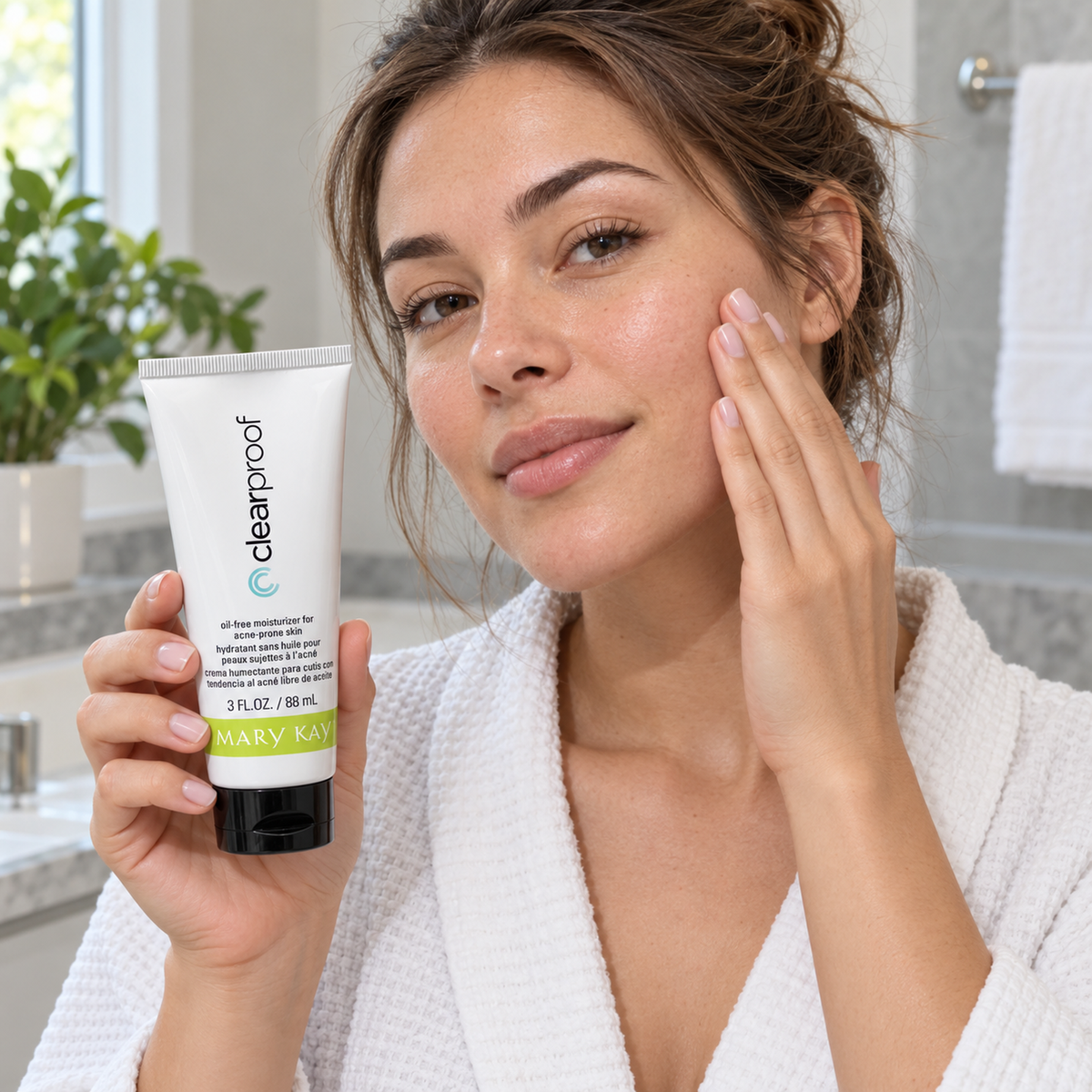 An adult touches her cheek with her fingertips while holding a closed Mary Kay Clear Proof moisturizer tube.