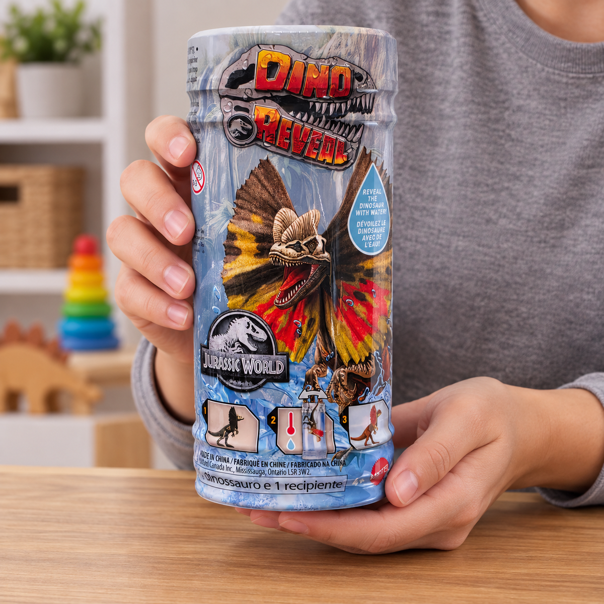 Hands holding one closed Jurassic World Dino Reveal canister with its front artwork visible.