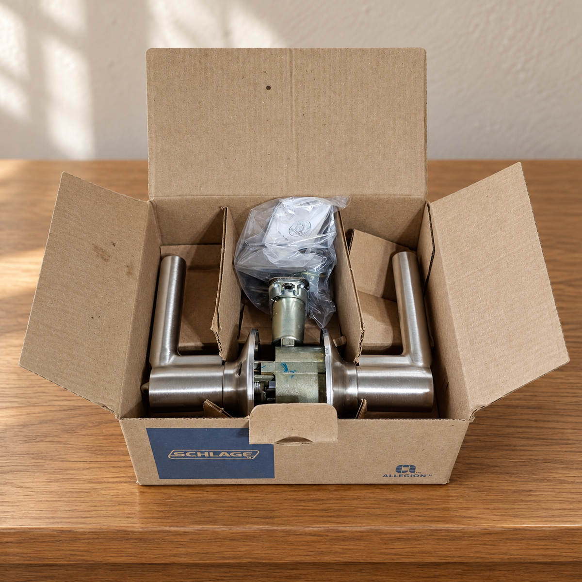 Schlage Broadway satin nickel lever pair in its open box on an oak console