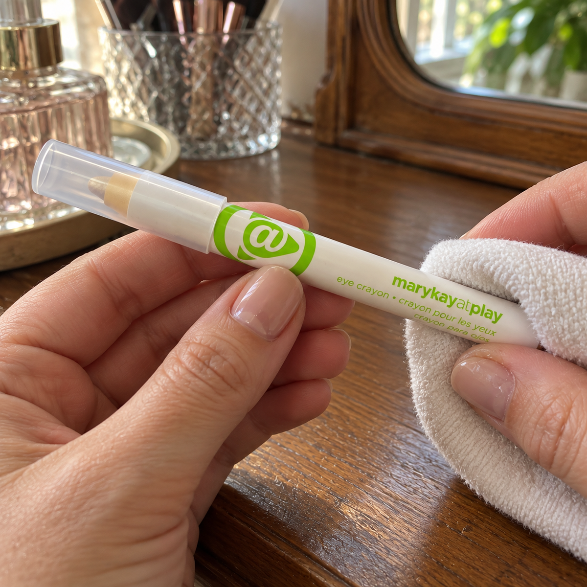 Wiping the outside of a capped Mary Kay At Play Gold Mine eye crayon with a soft cloth.