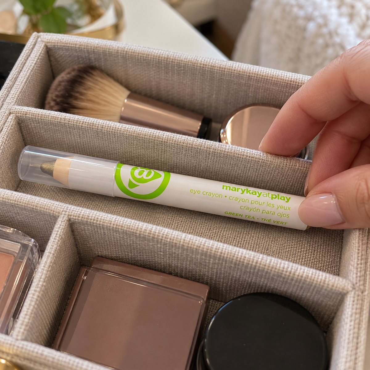 Placing a capped Green Tea eye crayon in a divided makeup organizer.
